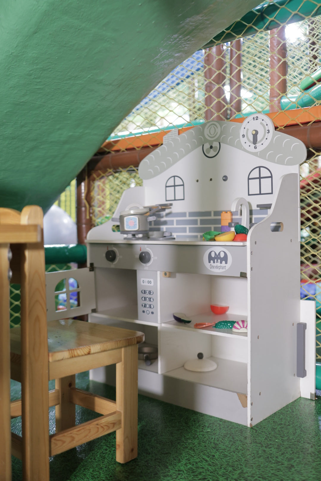 Children's play structure with slides and climbing elements on a green floor.