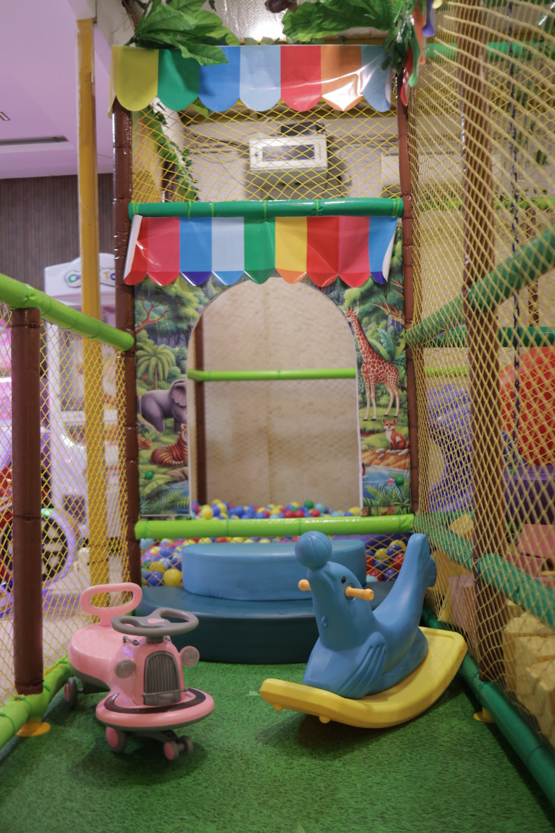 Indoor play section with colorful canopy, animal murals, ball pit, and ride-on toys at Jumping Jollies Sector 104 Hazipur Noida
