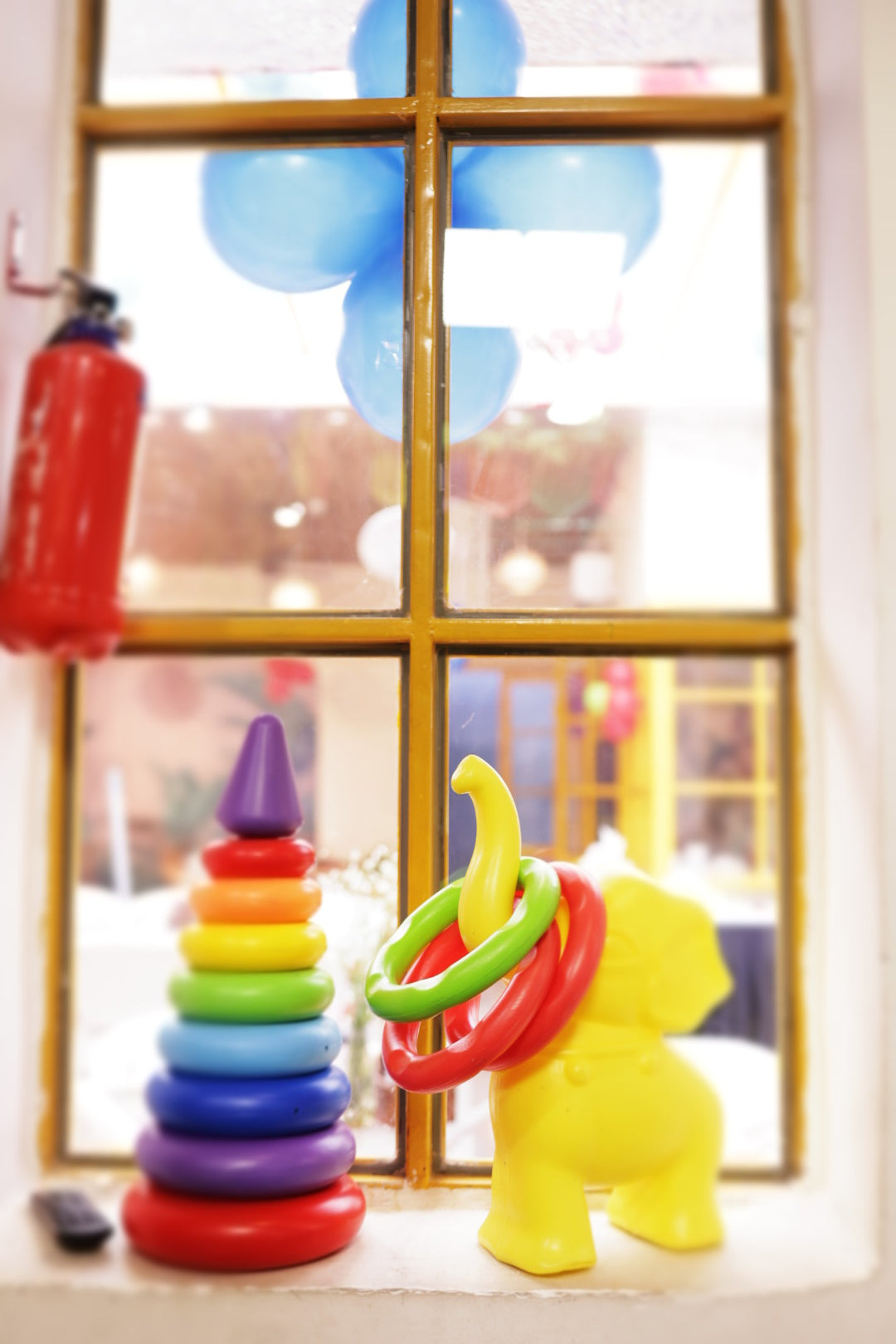 Colorful stacking rings and yellow toy elephant with rings displayed on window ledge at indoor play area Sector 104 Hazipur