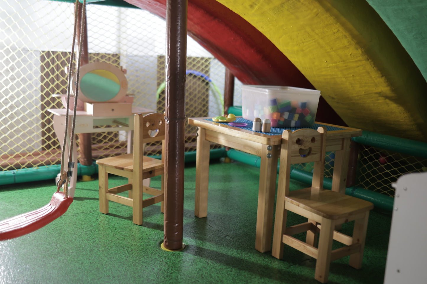Small wooden activity table and chairs under colorful tunnel structure inside Jumping Jollies play area Sector 104 Hazipur