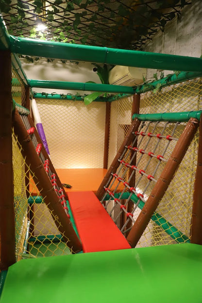 Compact indoor climbing structure with red ramp and rope nets surrounded by yellow safety mesh at Jumping Jollies Sector 104 Hazipur