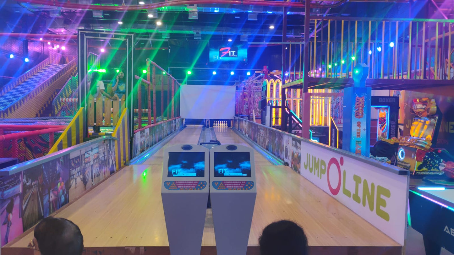 Bowling alley in an arcade with colorful lights and people playing.