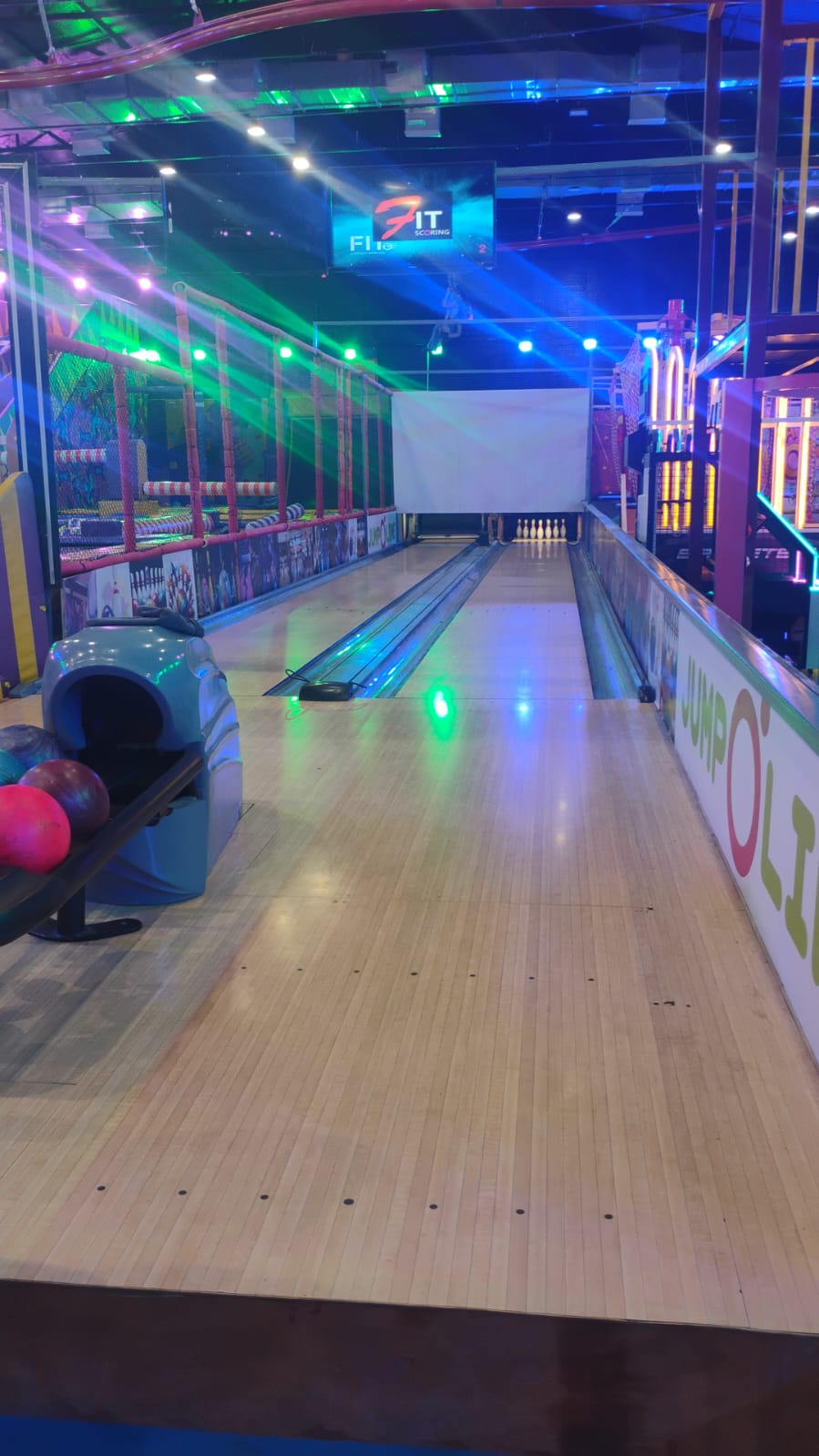 A bowling alley with colorful lights and pins set up.