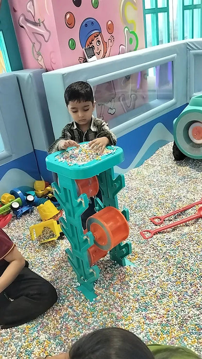 A young boy plays with a colorful toy in a ball pit.