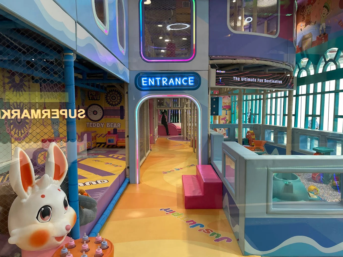 A colorful indoor playground with a bunny mascot and a neon "Entrance" sign.