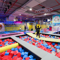 People jumping on trampolines and in a foam pit at an indoor amusement park.