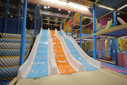 A colorful indoor playground with three slides decorated with musical notes, suitable for children.