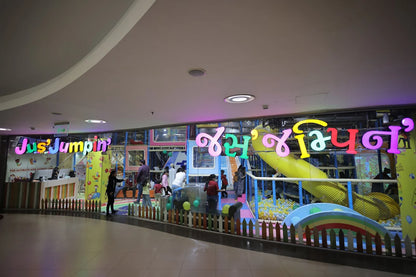 A colorful indoor play area for children with a "Jus' Jumpin'" sign and a slide into a ball pit.