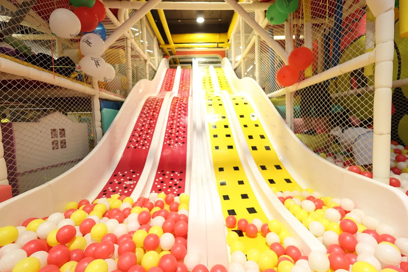 A colorful indoor playground with multiple slides and a ball pit, designed for children.