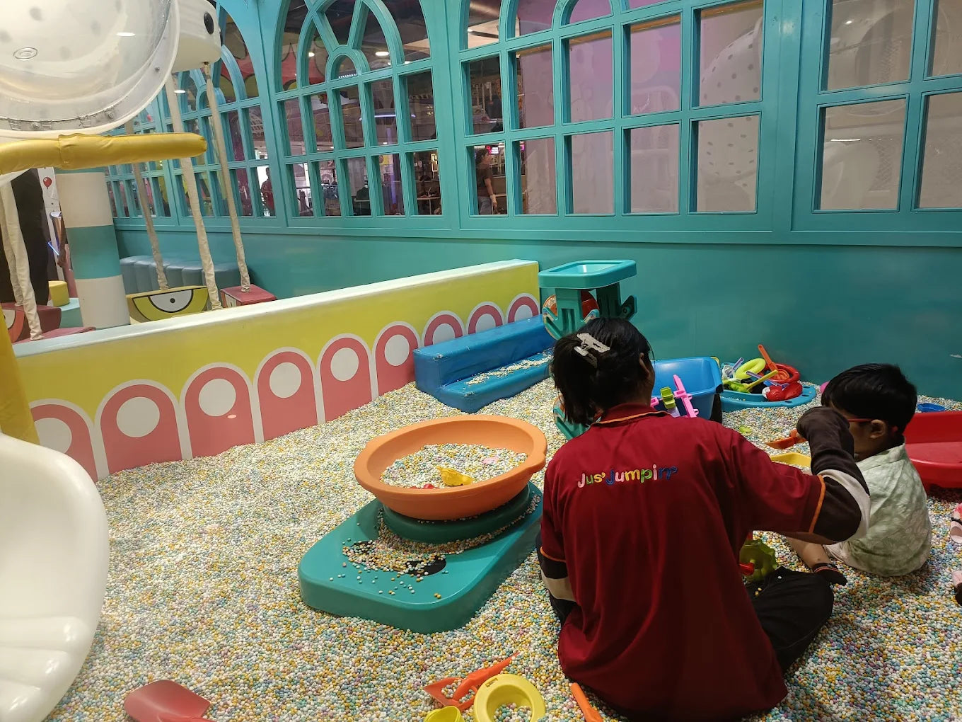 Children play in a ball pit at an indoor playground.