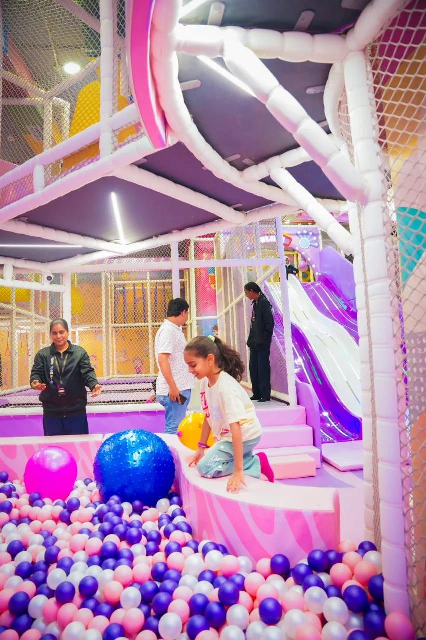 Children play in a colorful ball pit with slides and climbing structures.