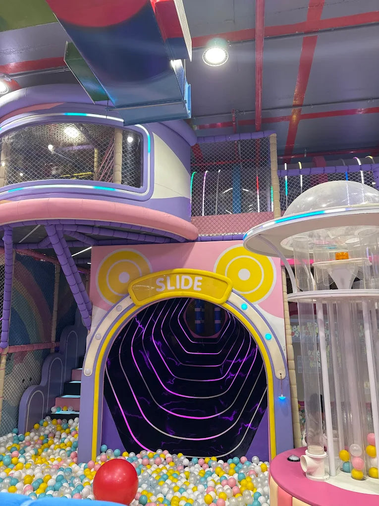 A colorful indoor playground with a ball pit, slide, and climbing structures for children.