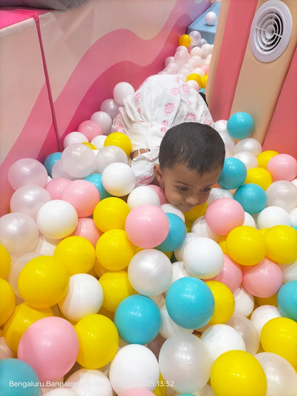 A young child plays in a ball pit filled with colorful balls.