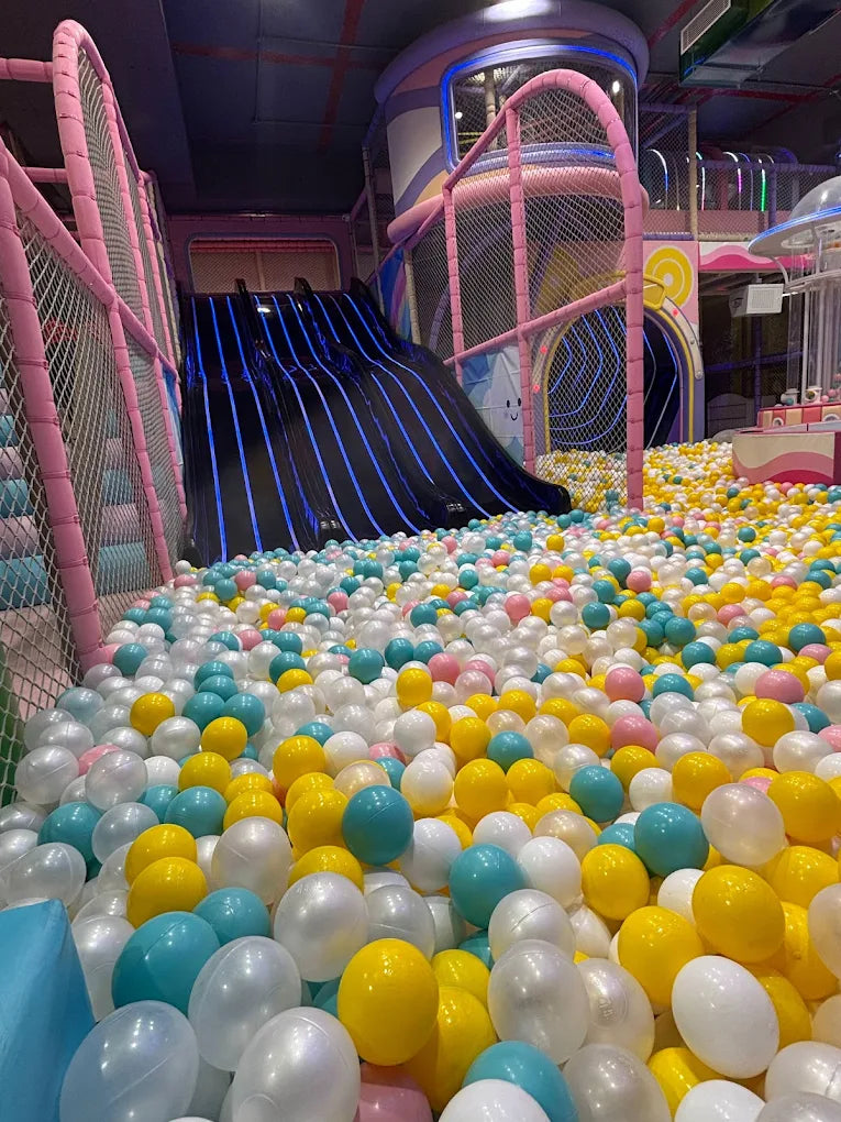 A colorful ball pit with a large slide in a children's play area.