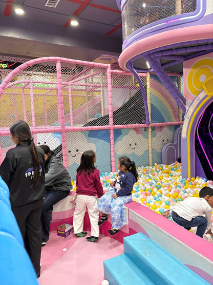 Children play in a colorful indoor playground with ball pits and slides.