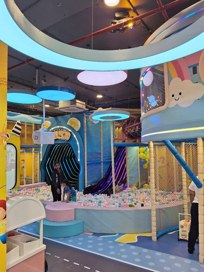 Children play in a colorful indoor ball pit with slides and climbing structures.