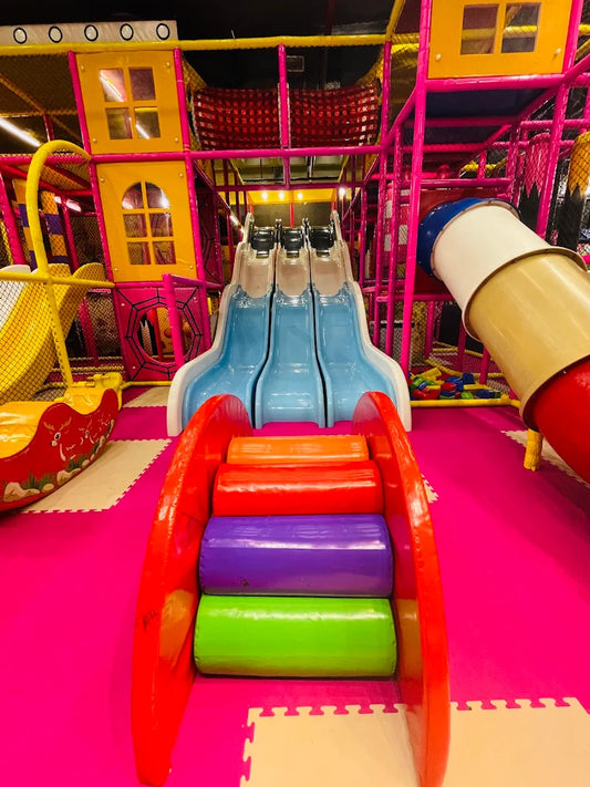 A colorful indoor playground with slides and soft climbing steps for children.