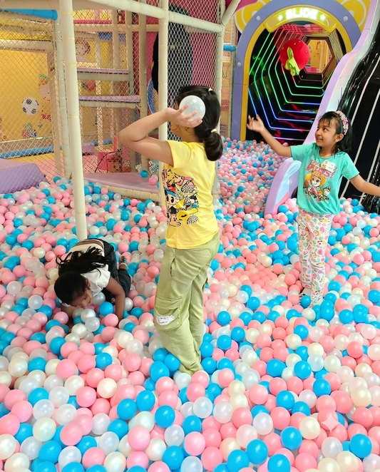 Children play in a ball pit at an indoor playground.