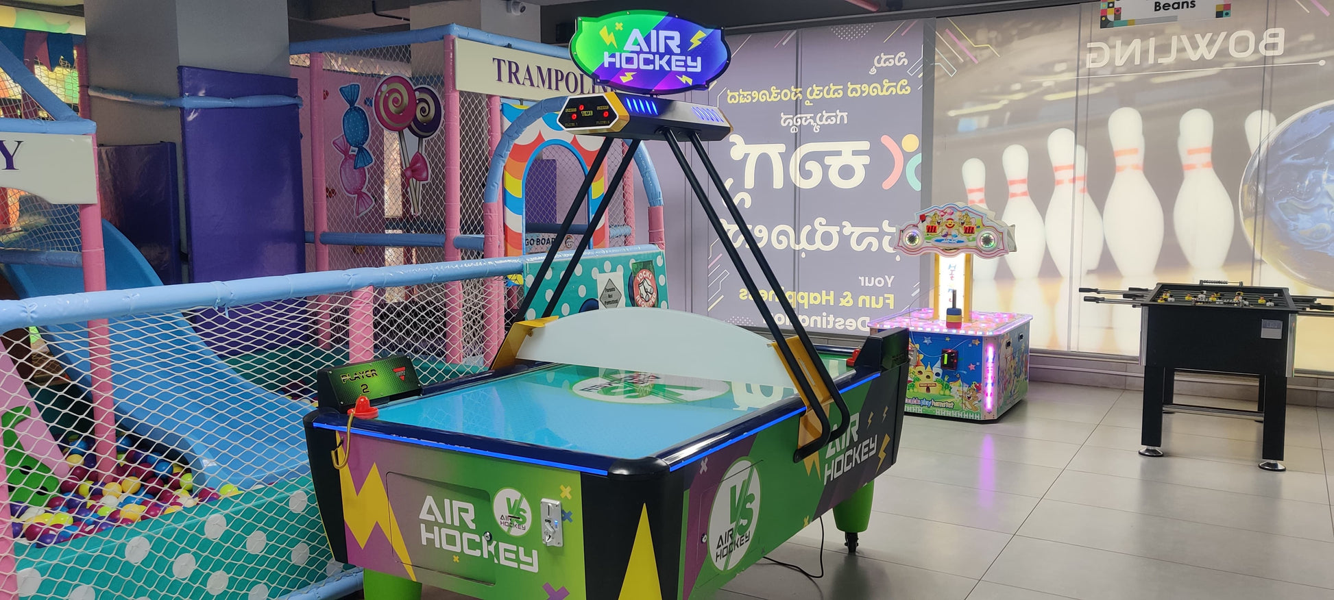An air hockey table and other arcade games in a brightly lit children's play area.