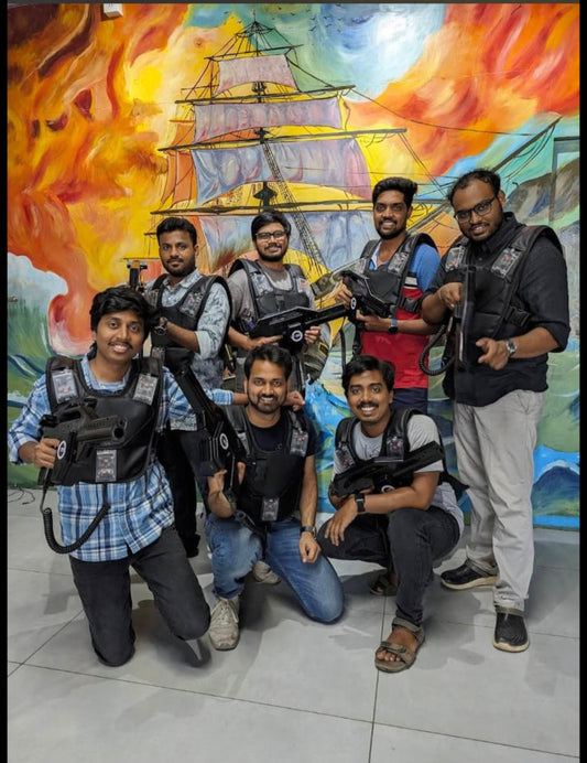 A group of young men in laser tag vests and gear pose in front of a mural of a ship.