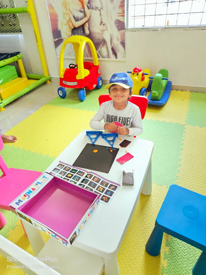 A young child sits at a table in a playroom, engaged in a magnetic play activity. Toys and colorful mats fill the background.