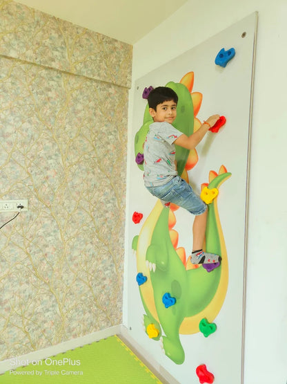 A young boy climbs a colorful dragon-themed wall with handholds.