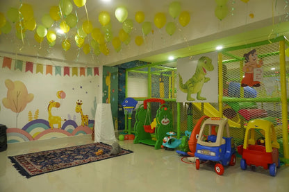A brightly decorated indoor play area for young children, featuring a soft play structure, toys, and colorful wall art.