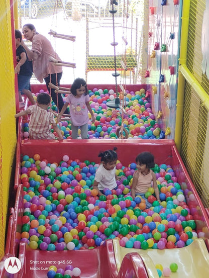 Children play in a ball pit at an indoor playground.
