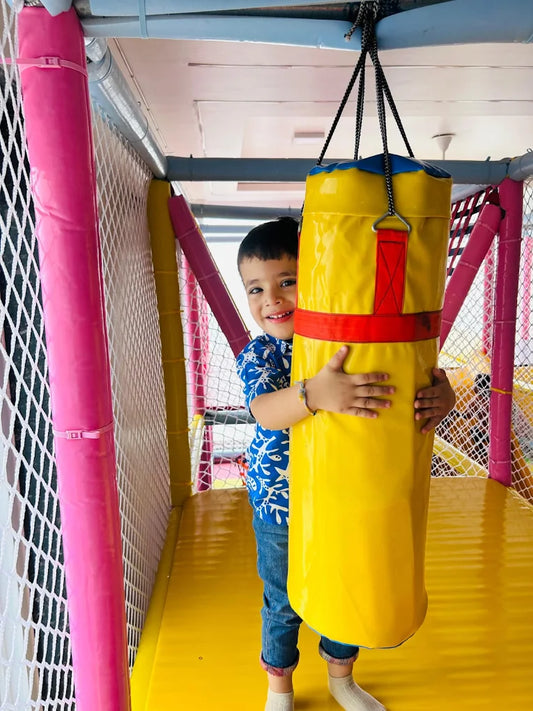 Child hugging a yellow punching bag in an indoor play area