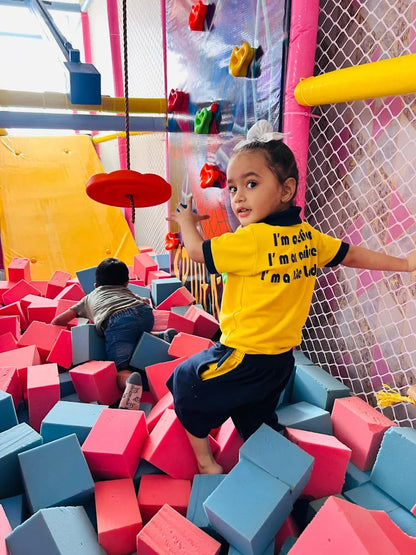 Child playing in a colorful foam pit with a play structure in the background