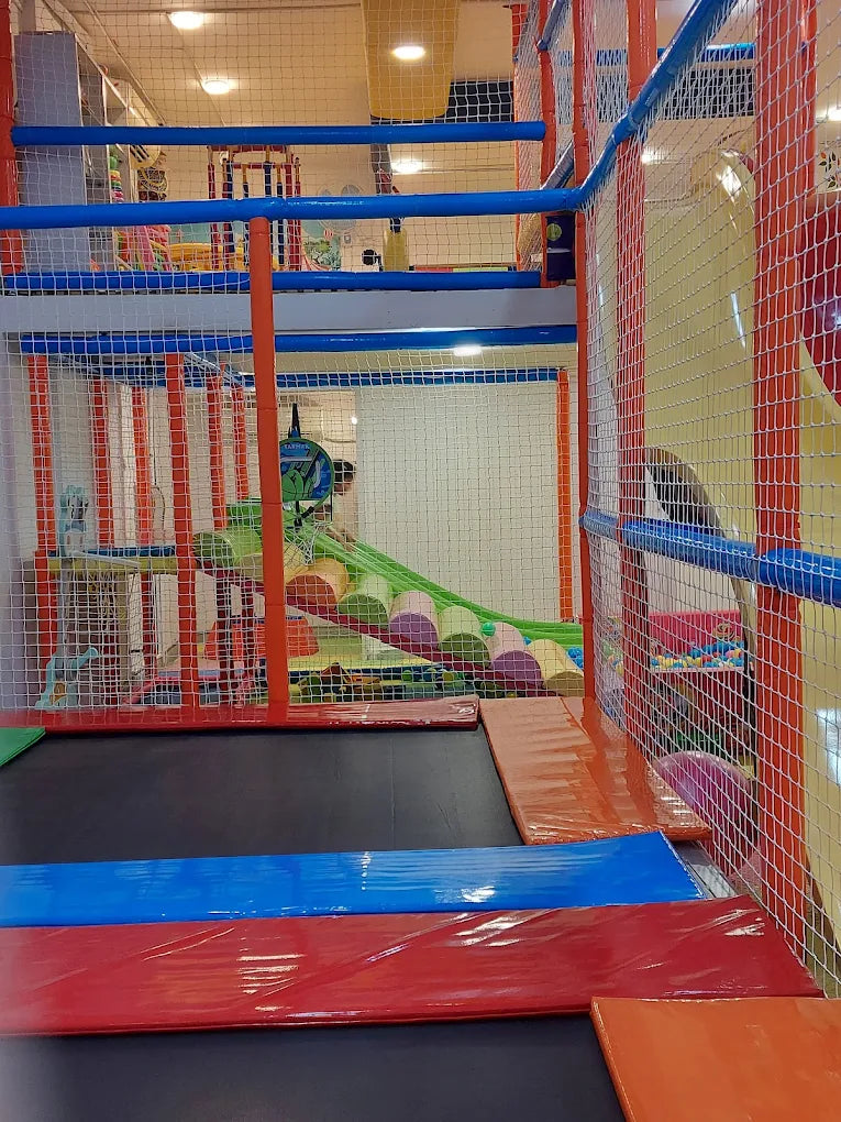 A colorful indoor playground with soft play structures and trampolines for children.