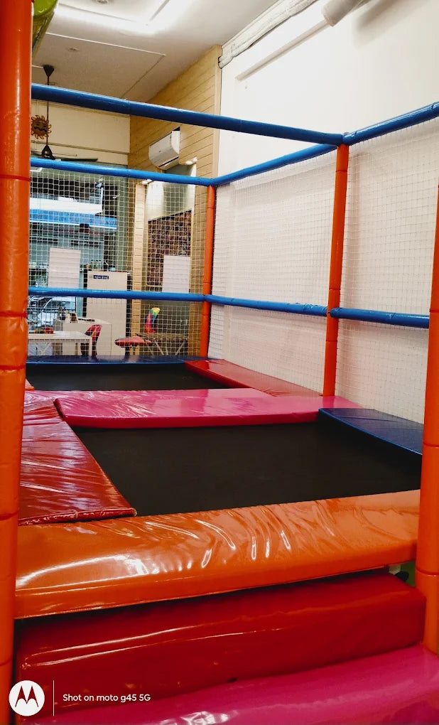 Indoor trampoline park with colorful padding and netting.