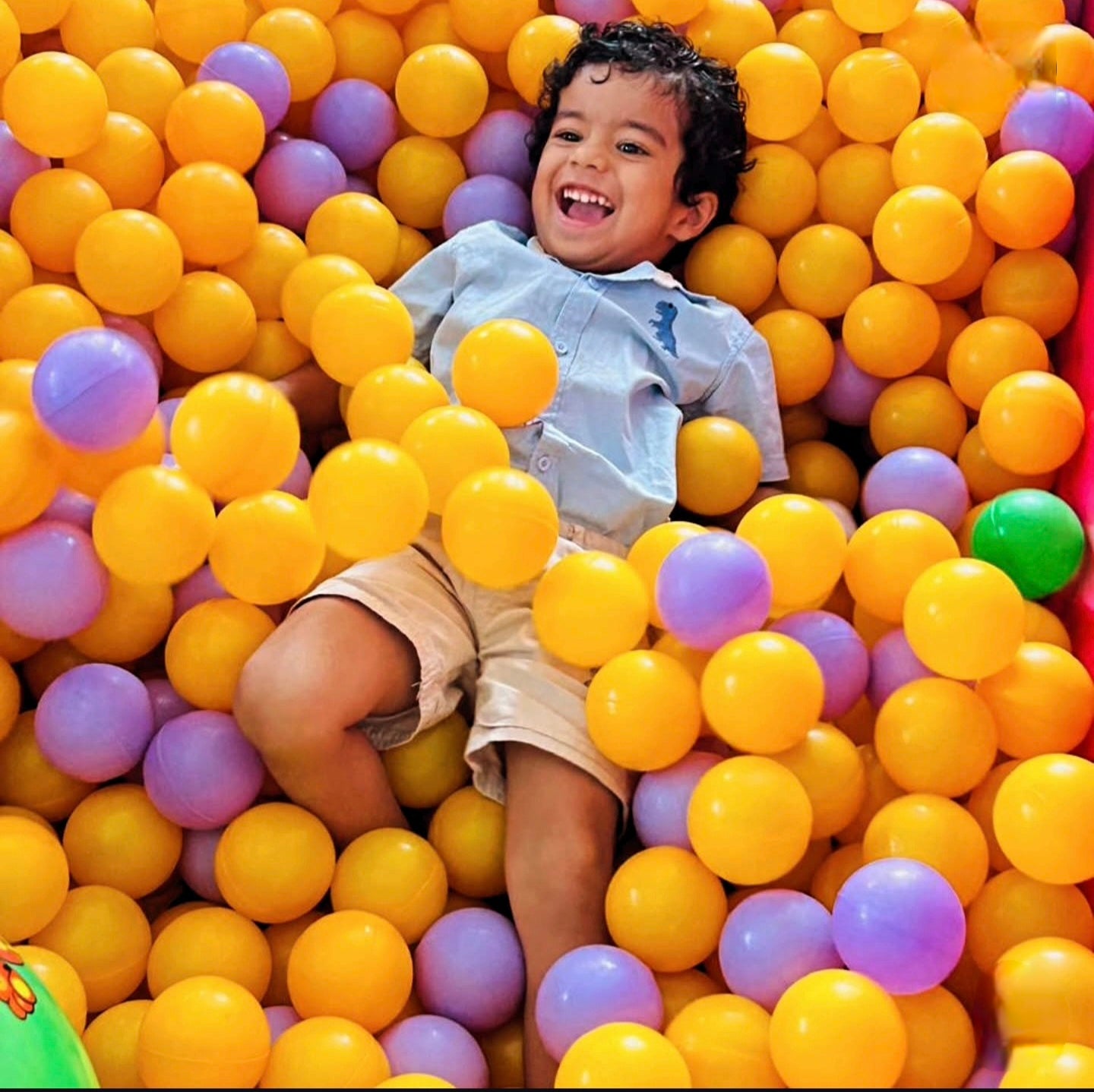 Child playing in a ball pit filled with colorful balls