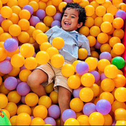 Child playing in a ball pit filled with colorful balls