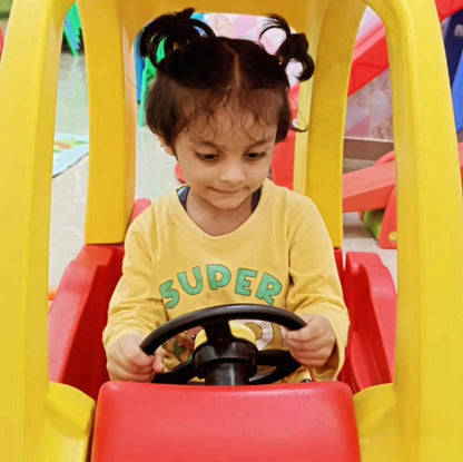 Child playing with a toy car, wearing a yellow shirt with 'SUPER' text.