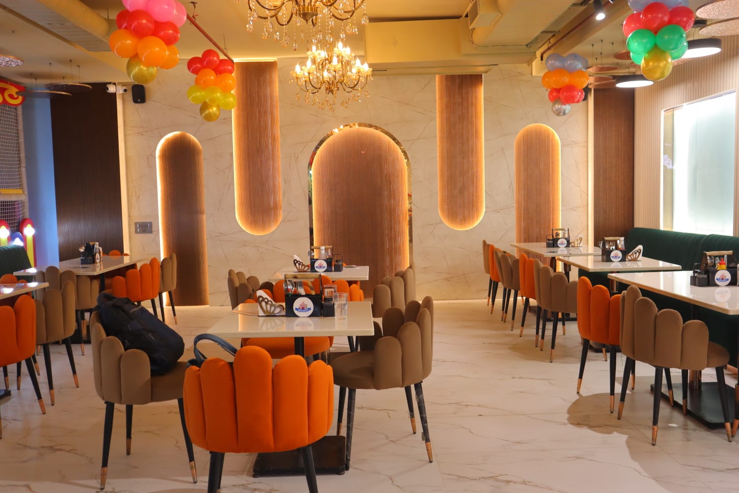 A restaurant dining area with marble floors, orange and brown chairs, and decorative balloons.