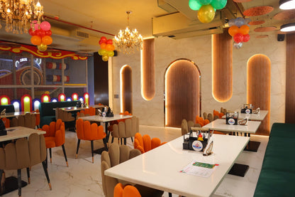 A brightly lit restaurant with colorful chairs and tables, decorated with balloons and chandeliers.