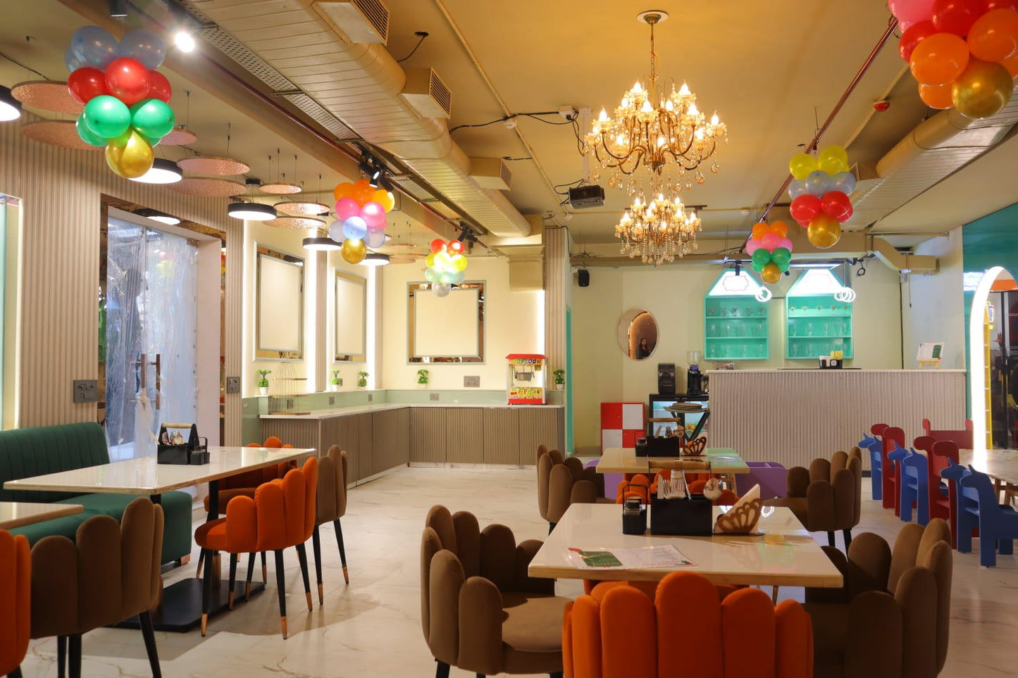 A brightly decorated restaurant interior with balloons, chandeliers, and colorful seating.