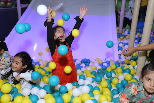 Children joyfully playing in a colorful ball pit with a glowing purple slide at Kiddtopia Sector 132 Noida event