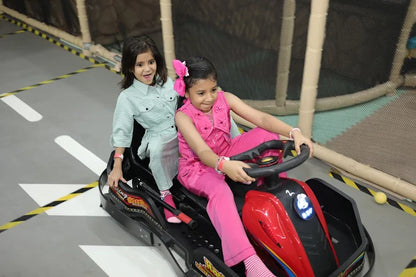 Two young girls playing with a toy car on a track indoors.