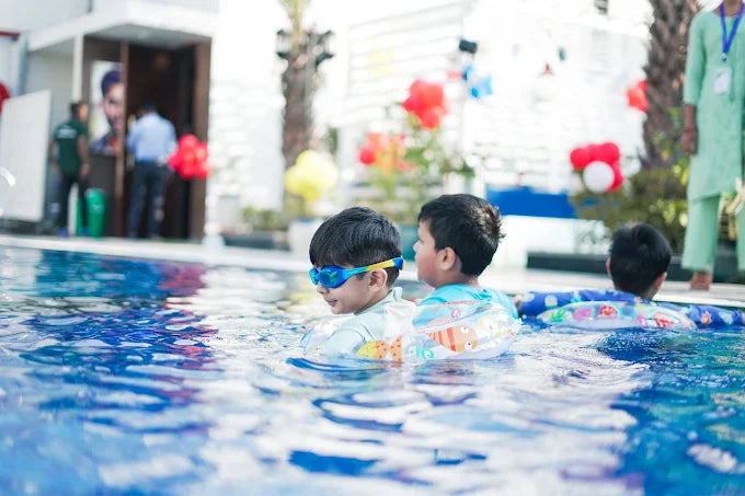 Children playing in a pool with swim aids and goggles.