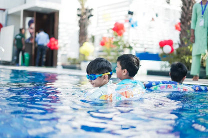 Children playing in a pool with swim aids and goggles.