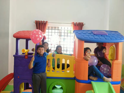 Children play in a colorful indoor playhouse with balloons.