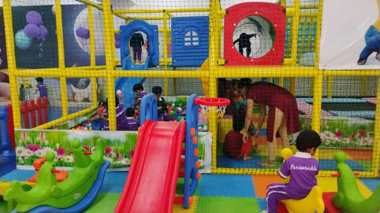 Children play in a colorful indoor playground with slides, ball pits, and climbing structures.