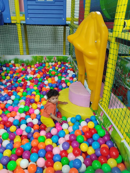 A toddler plays in a ball pit at an indoor playground.