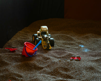 A sandbox with toy construction vehicles and a bucket.