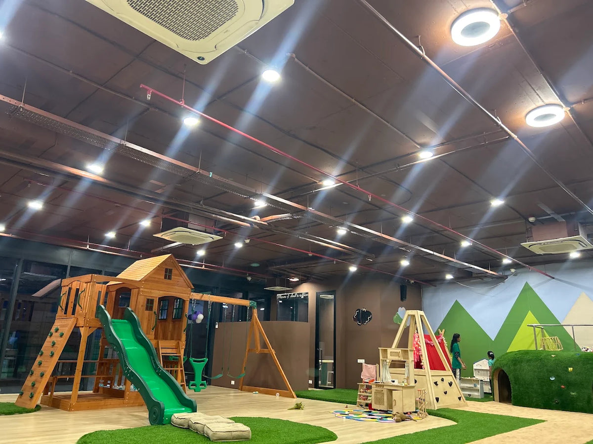 Children play in a colorful indoor playground with slides, swings, and climbing structures.