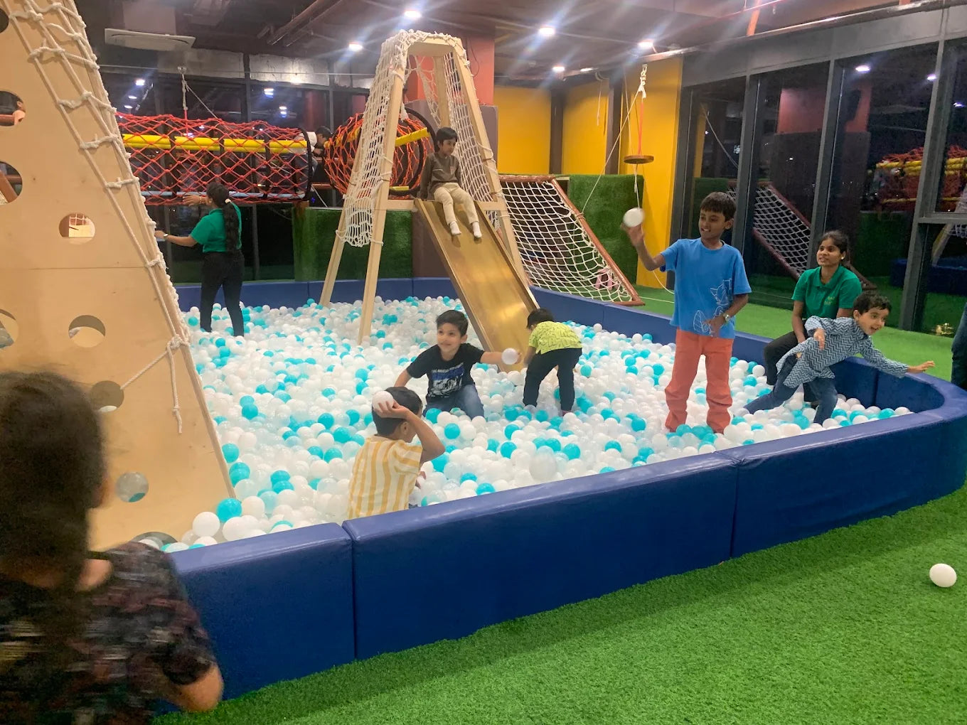 Children play in a ball pit at an indoor playground.