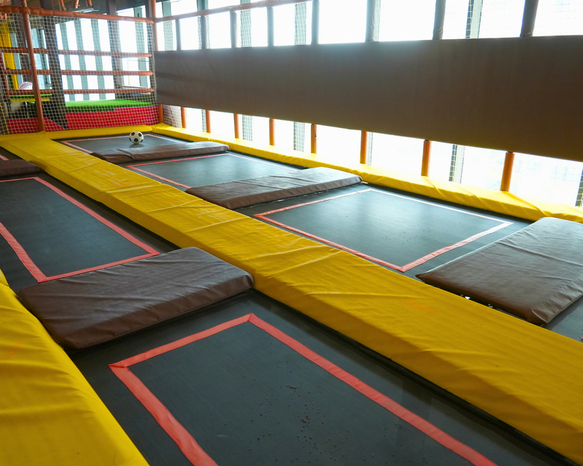 Indoor trampoline park with a soccer ball on a trampoline.