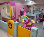 A colorful indoor play area for young children with a bouncy castle and soft play structures.